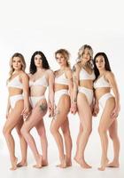 groupe de femmes différentes portant de la lingerie blanche sur fond gris. photo