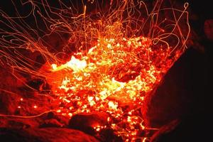 gros plan d'un feu de camp qui brûle vivement la nuit en jetant des étincelles. photo