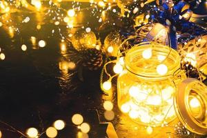 cadeau de noël avec ruban bleu et boules de décoration de noël sur fond noir abstrait bokeh avec espace de copie et lumières LED décoratives. joyeux noël et nouvel an.
