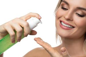 jeune femme à la peau lisse tenant une bouteille de gel nettoyant vert photo