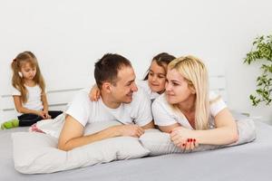 une jeune famille avec de jeunes enfants au lit dans la chambre photo