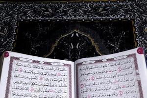 al-quran qui est au-dessus du tapis de prière avec un fond noir photo