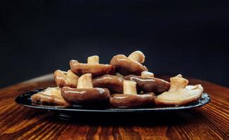 champignons marinés dans une assiette noire sur une table en bois. nourriture de village saine. champignon de lait noir mariné . photo