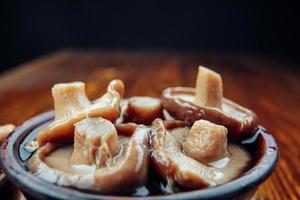 champignons marinés rustiques très savoureux dans une tasse d'argile sur une table en bois. la nourriture saine . photo