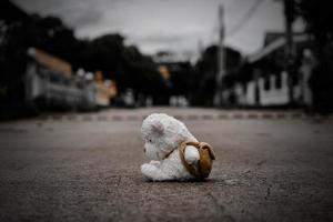 L'ours en peluche solitaire dort sur le sol en ciment pour une carte postale créée d'enfants disparus internationaux, un cœur brisé, une poupée mignonne solitaire, triste et non désirée perdue. photo