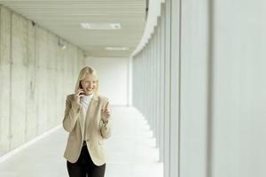 femme d'affaires utilisant un téléphone portable dans un couloir de bureau moderne photo