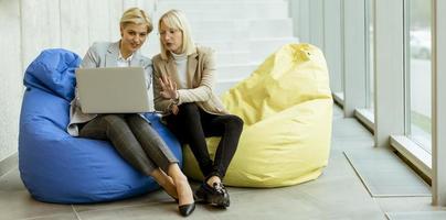 femmes d'affaires utilisant un ordinateur portable sur des sacs paresseux dans le bureau moderne photo