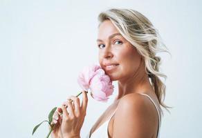 Portrait de beauté de cheveux blonds jeune femme souriante avec pivoine rose à la main isolé sur fond blanc photo