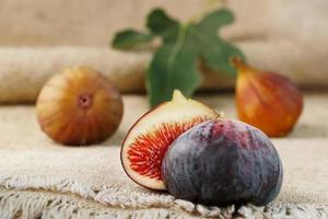 figues biologiques mûres sur la table. groupe de figues violettes et vertes sur une table en bois de ferme avec toile de jute photo