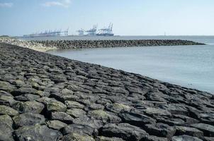 bord de mer est fortifié avec des pierres de lavage par l'eau, un port peut être vu en arrière-plan. beau paysage marin. photo