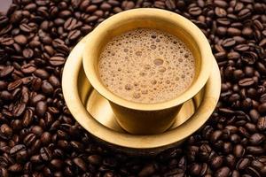 café filtre du sud de l'inde servi dans un gobelet traditionnel ou une tasse sur des grains crus torréfiés photo