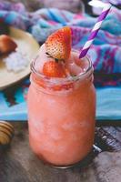 jus de smoothie aux fraises, sur le miel de garniture savoureux pour l'été sur table en bois, jus d'eau douce pour la santé