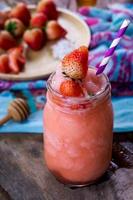 jus de smoothie aux fraises, sur le miel de garniture savoureux pour l'été sur table en bois, jus d'eau douce pour la santé