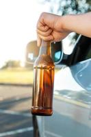 conducteur de voiture tenant une bouteille de bière photo