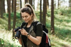 randonneur utilisant un appareil photo sans miroir moderne dans la forêt verte