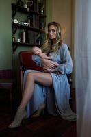 jeune belle mère vêtue d'une robe grise de luxe tenant son bébé sur les mains photo