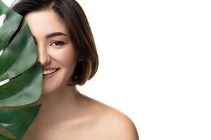 portrait de jeune belle femme brune avec une feuille tropicale de monstera deliciosa photo