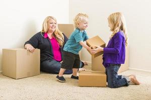 jeune famille dans une pièce vide avec des cartons de déménagement photo