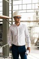 homme architecte ou homme d'affaires portant un casque et tenant des plans sur un chantier de construction photo