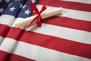 Diplôme enveloppé de ruban reposant sur le drapeau américain avec copie espace photo
