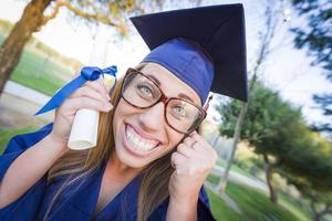 jeune femme expressive titulaire d'un diplôme en bonnet et robe photo