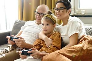 une famille heureuse joue à la console de jeux vidéo à la maison photo