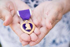 femme âgée tenant la médaille militaire du cœur violet dans ses mains. photo