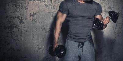 bodybuilder fait des boucles de biceps avec des haltères photo