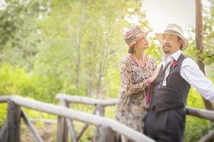 Couple romantique habillé des années 1920 sur un pont en bois photo