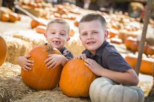 deux garçons s'amusant au champ de citrouilles un jour d'automne. photo