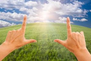 mains féminines faisant un cadre sur l'herbe et le ciel photo