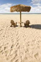 deux chaises de plage et un parasol sur le magnifique sable de l'océan photo