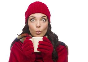 une femme de race mixte aux yeux écarquillés portant des gants d'hiver tient une tasse photo