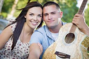 portrait de couple mixte avec guitare dans le parc photo