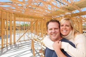 heureux couple excité sur place à l'intérieur de leur nouvelle charpente de construction de maison. photo