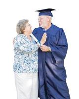 Diplômé de l'homme adulte senior en bonnet et robe d'être félicité par la femme isolé sur blanc. photo