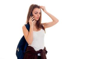 beauté jeune fille étudiante brune avec sac à dos téléphone parlant isolé sur fond blanc photo