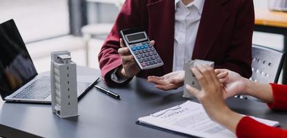 discussion avec un agent immobilier, modèle de maison avec agent et client discutant du contrat d'achat, d'assurance ou de prêt immobilier ou immobilier. photo