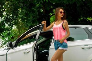 jolie femme de mode à lunettes et short court ouvre la portière de la voiture photo