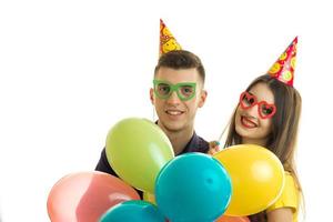 le jeune garçon souriant et la fille joyeuse portant des lunettes colorées et portant des ballons photo