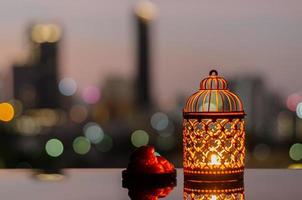 lanterne dorée et fruits de dattes avec ciel d'aube et fond clair bokeh de la ville pour la fête musulmane du mois sacré du ramadan kareem. photo