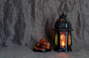 lanterne noire et fruits de dattes sur fond de tissu sombre pour la fête musulmane du mois sacré du ramadan kareem. photo