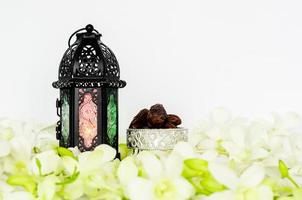 lanterne sur fond blanc avec des fruits de dattes sur une fleur d'orchidée pour la fête musulmane du mois sacré du ramadan kareem. photo