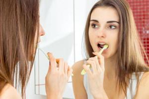 jolie jeune fille se tient dans la salle de bain se regarde dans le miroir et se brosse les dents photo