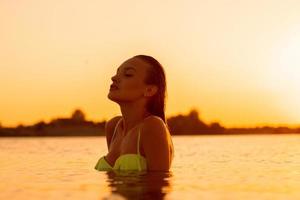 jeune femme sexuelle dans la mer au coucher du soleil chaud photo