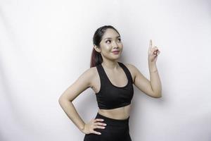 femme sportive asiatique excitée portant des vêtements de sport pointant vers l'espace de copie au-dessus d'elle, isolée par fond blanc photo