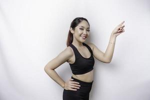 femme sportive asiatique excitée portant des vêtements de sport pointant vers l'espace de copie à côté d'elle, isolée par fond blanc photo