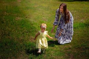 joyeuse jeune mère joue avec sa petite fille dans le jardin verdoyant photo