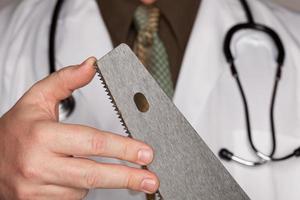 médecin avec stéthoscope tenant une scie tranchante photo