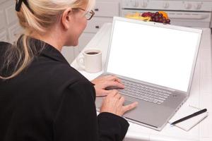 femme dans la cuisine à l'aide d'un ordinateur portable avec écran vide photo